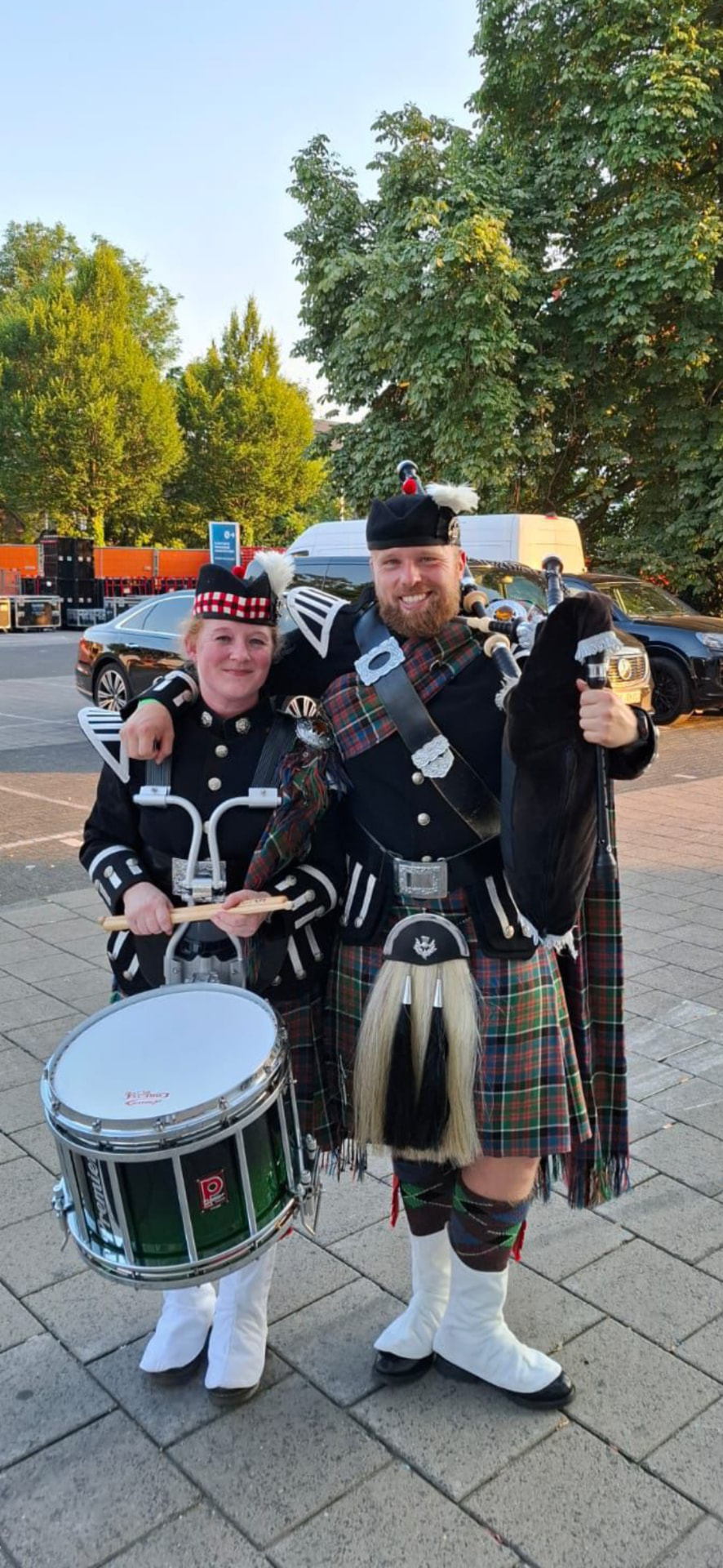 Bruce Korthout als piper naast zijn vrouw Alicia als drummer, beiden in vol ornaat met kilt en Highland Dress voor een optreden